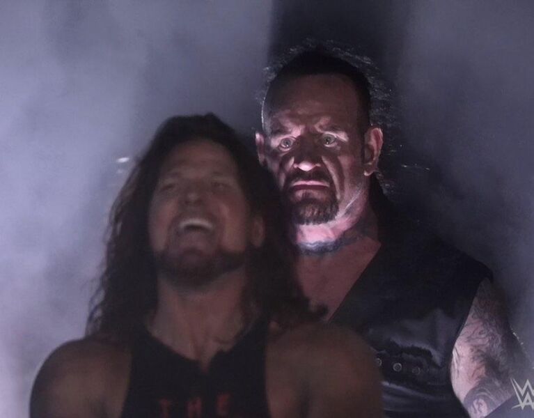 File:Undertaker Standing Behind AJ Styles.jpg